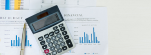 Calculatrice posée sur des documents financiers avec graphiques et tableaux de budget.