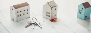 Clés posées sur des graphiques financiers avec des maisons miniatures, symbolisant un investissement immobilier