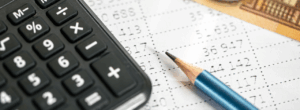 Calculatrice, crayon et document chiffré représentant le calcul des cotisations et l’analyse de la masse salariale en entreprise.