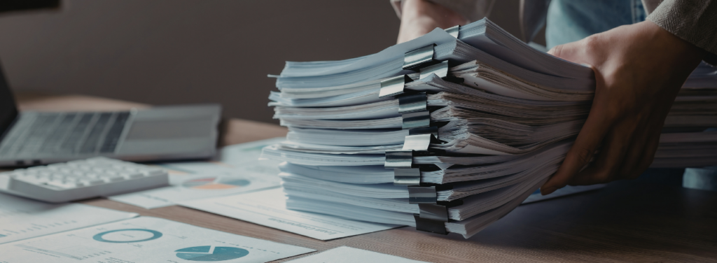Des piles de documents administratifs et financiers, symbolisant le défi quotidien de la gestion pour les associations.
