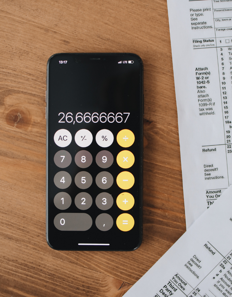 Un téléphone portable affichant un calcul financier, avec des documents fiscaux à côté, symbolisant l'optimisation fiscale pour les infirmiers libéraux.