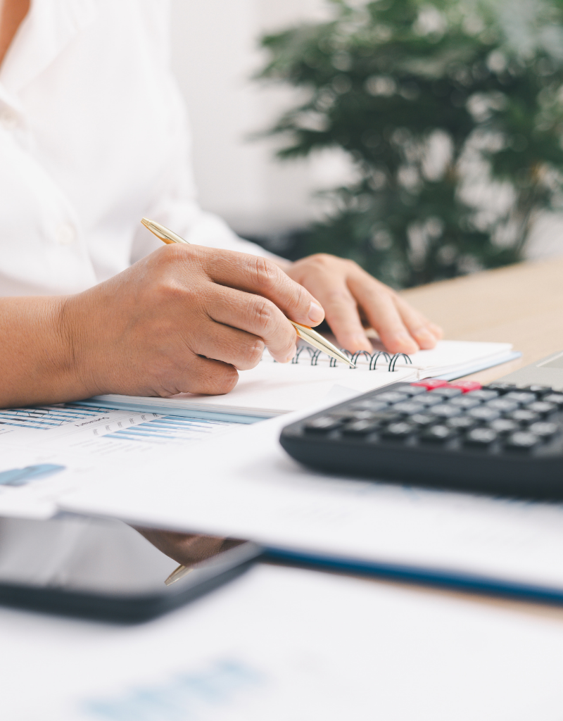 Personne calculant ses impôts avec calculatrice et carnet pour optimiser la fiscalité des dividendes