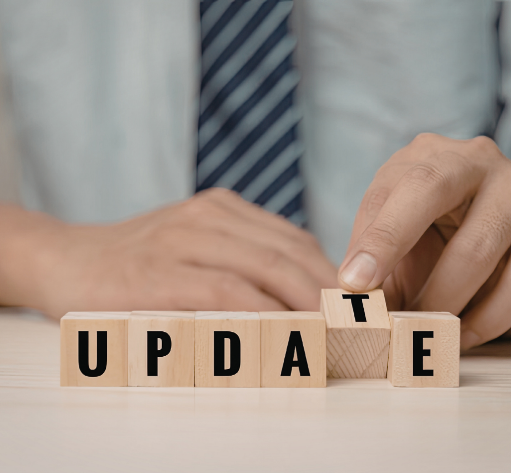 Image d'une main ajustant les lettres sur des blocs de bois pour former le mot "UPDATE", symbolisant la mise à jour des logiciels et systèmes d'exploitation.