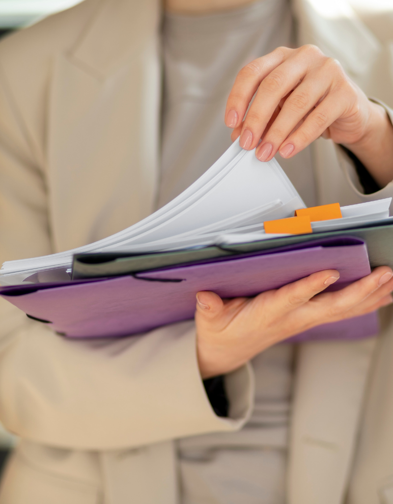 Personne consultant un dossier rempli de documents et de factures classés par onglets.