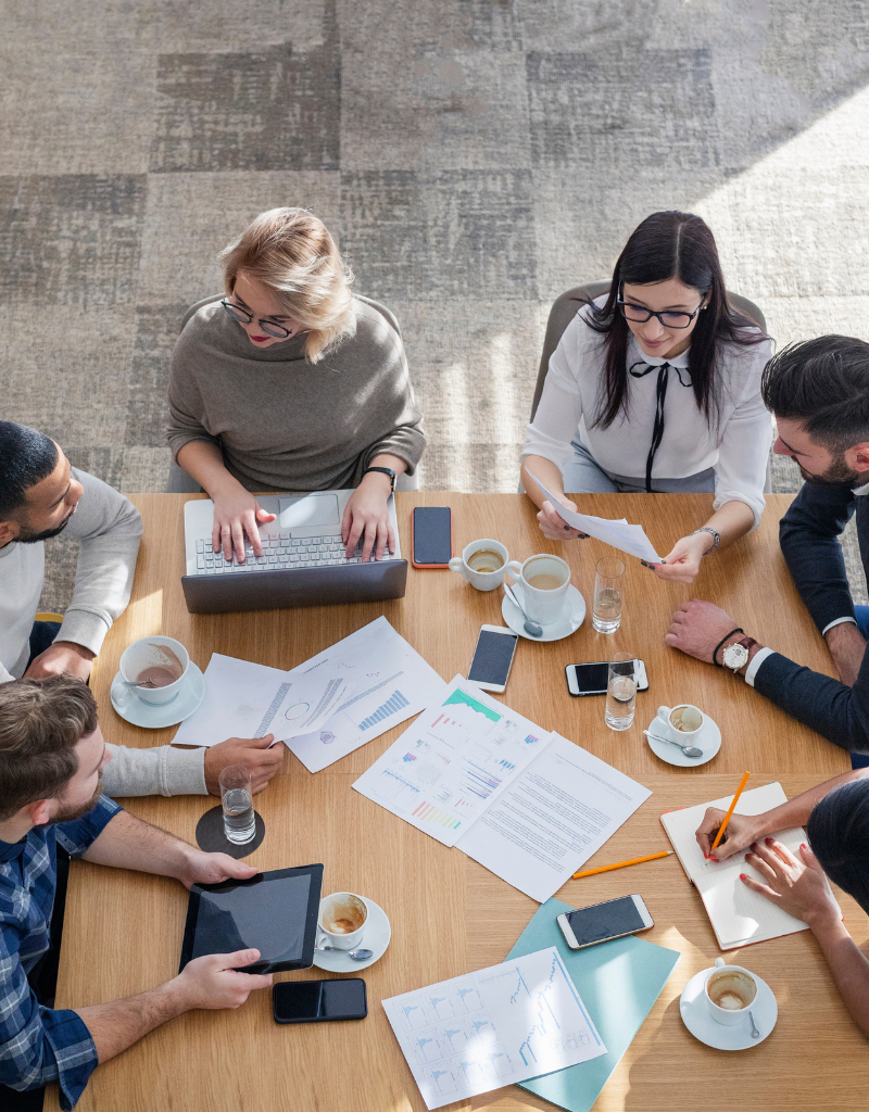 Plusieurs professionnels réunis autour d’une table analysent des documents pour structurer un projet d’entreprise à plusieurs associés.