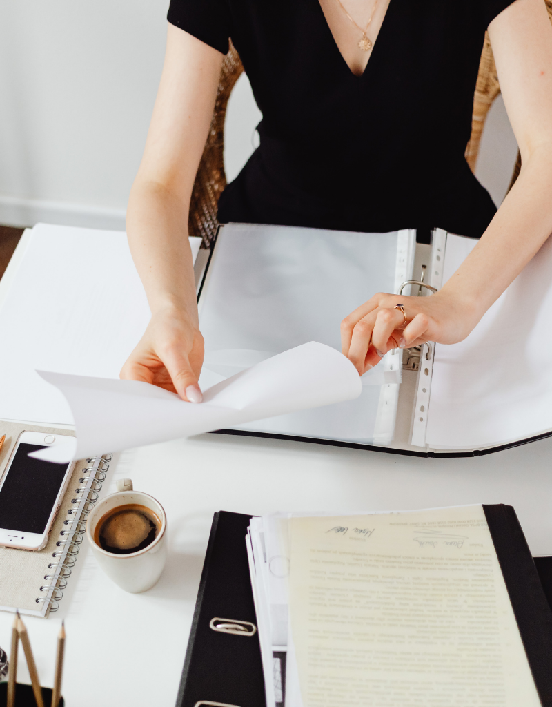 Femme classant des documents administratifs dans un classeur, illustrant l’identification d’une entreprise par son numéro SIREN.